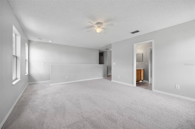 carpeted spare room with a textured ceiling and ceiling fan