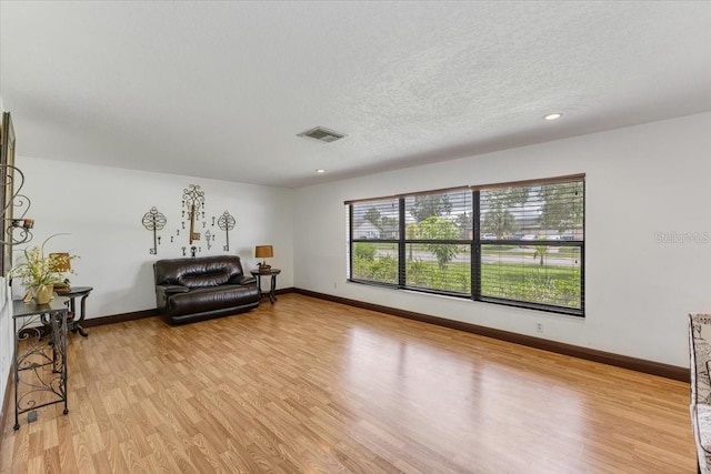 living area featuring a textured ceiling and light hardwood / wood-style flooring