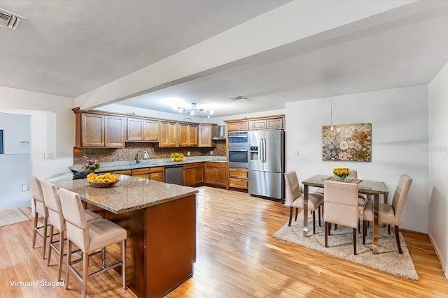 kitchen featuring a breakfast bar, stainless steel appliances, light stone counters, decorative backsplash, and kitchen peninsula