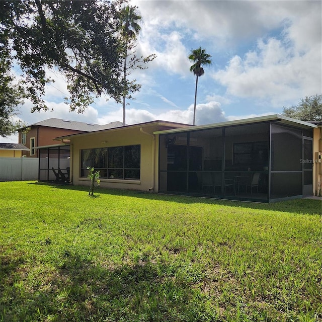 rear view of house featuring a yard and a sunroom