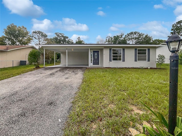 ranch-style home with an attached carport, fence, stucco siding, a front lawn, and aphalt driveway