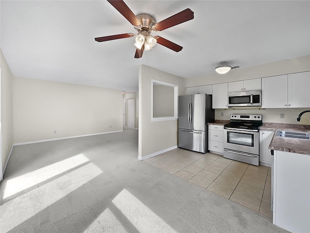 kitchen featuring stainless steel appliances, sink, light colored carpet, ceiling fan, and white cabinets