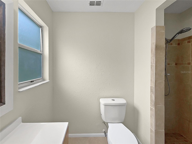 bathroom featuring vanity, toilet, and a tile shower