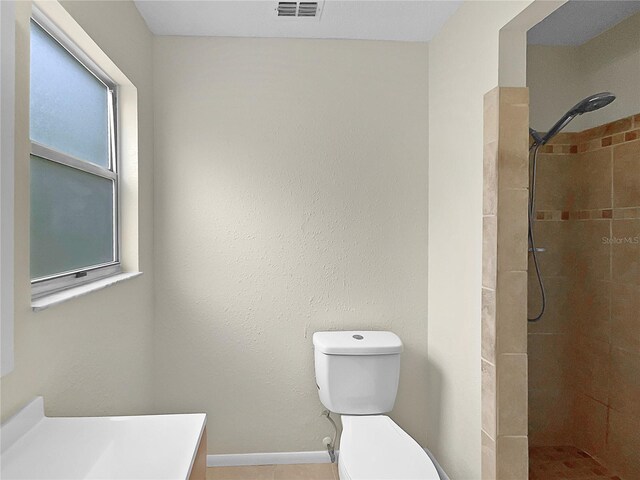 bathroom with vanity, toilet, and a tile shower