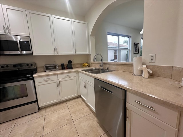 kitchen with white cabinets, stainless steel appliances, kitchen peninsula, and sink