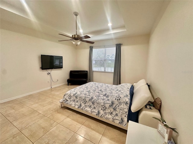 tiled bedroom with a tray ceiling and ceiling fan