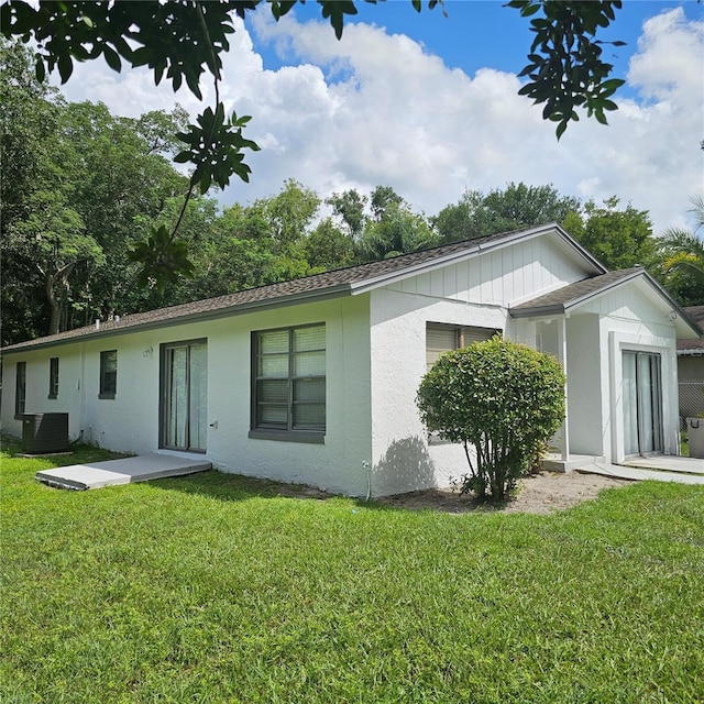 back of house with central AC unit and a lawn