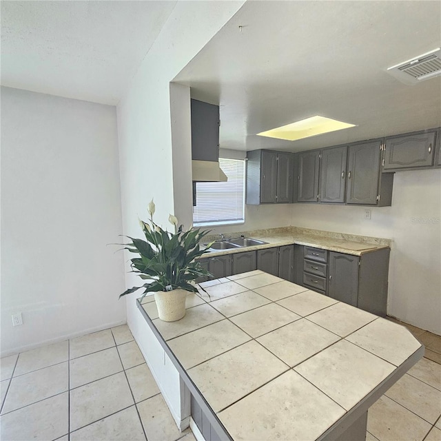 kitchen with tile countertops, sink, and light tile patterned flooring