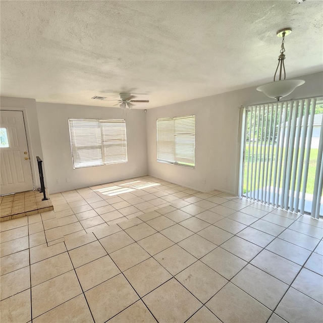 unfurnished living room with a textured ceiling, ceiling fan, and light tile patterned floors