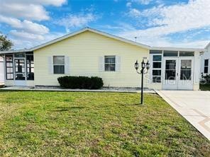 rear view of house with a yard and a sunroom