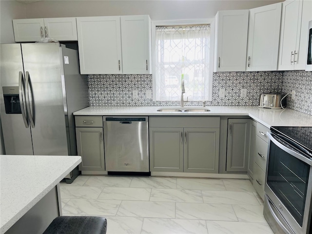 kitchen featuring white cabinets, appliances with stainless steel finishes, sink, gray cabinets, and decorative backsplash