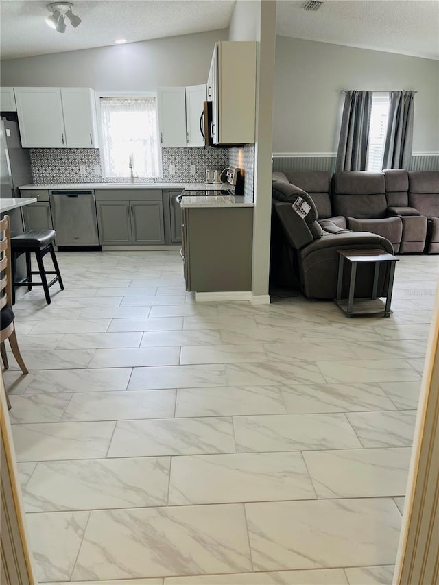 kitchen with marble finish floor, appliances with stainless steel finishes, open floor plan, and vaulted ceiling