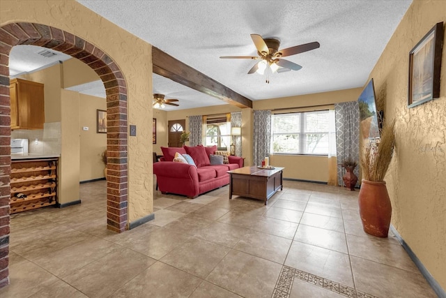 living room with beam ceiling, ceiling fan, and a textured ceiling