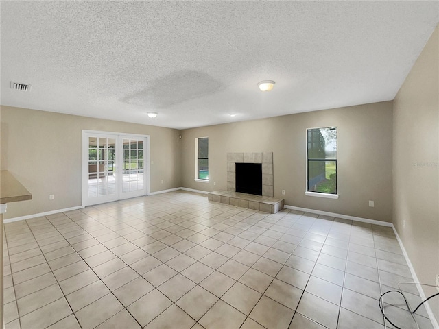 unfurnished living room featuring a textured ceiling, a fireplace, and light tile patterned floors