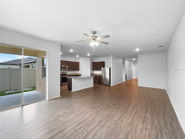 unfurnished living room with ceiling fan, sink, and hardwood / wood-style flooring