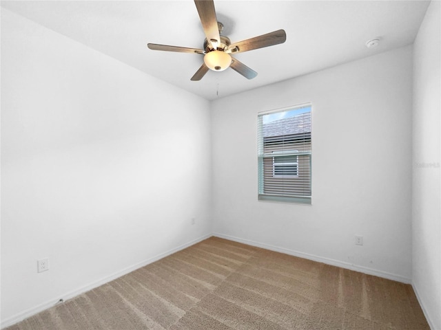 carpeted spare room with a ceiling fan and baseboards