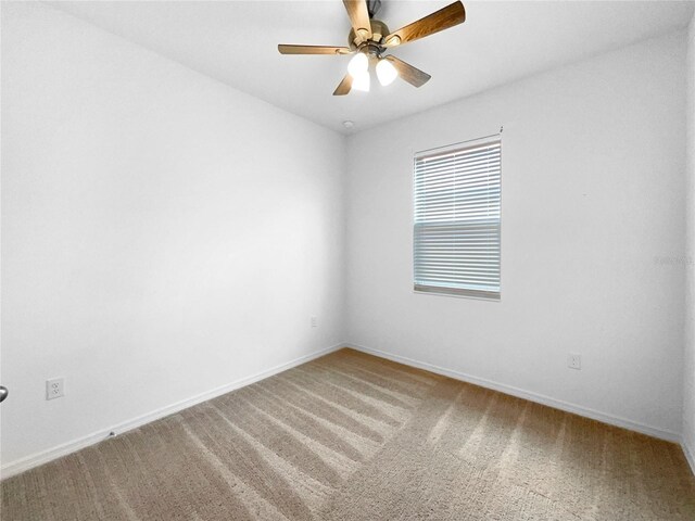 carpeted empty room featuring ceiling fan and baseboards