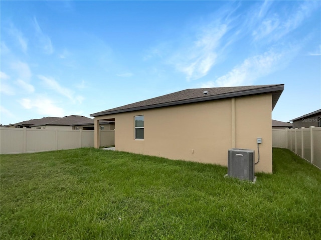 rear view of property with a fenced backyard, central air condition unit, stucco siding, and a yard