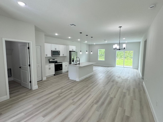 kitchen with an inviting chandelier, an island with sink, stainless steel appliances, light wood-type flooring, and white cabinets