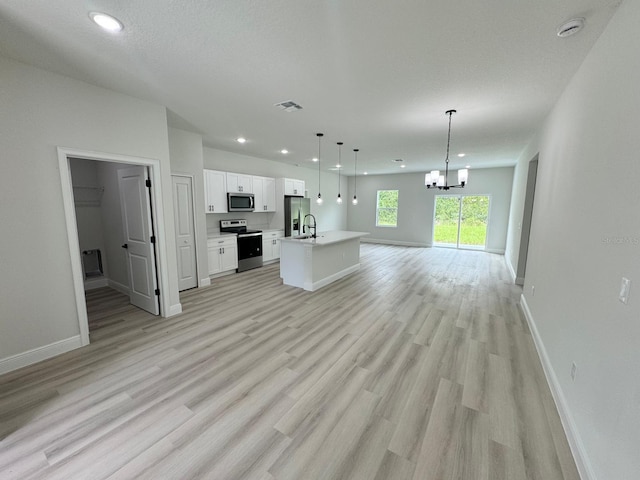 unfurnished living room with a textured ceiling, light hardwood / wood-style flooring, sink, and a notable chandelier