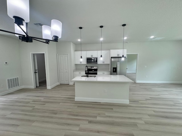 kitchen with light wood-type flooring, pendant lighting, sink, appliances with stainless steel finishes, and white cabinets