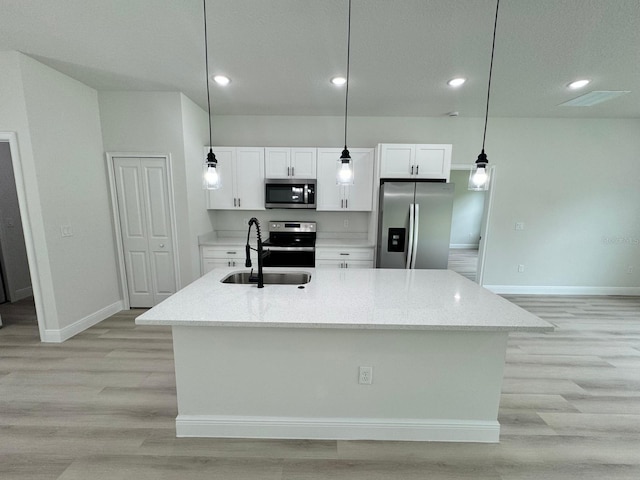 kitchen with pendant lighting, a kitchen island with sink, stainless steel appliances, light stone counters, and white cabinets