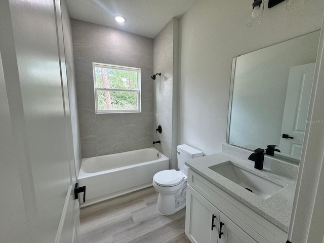 full bathroom with hardwood / wood-style floors, toilet, tiled shower / bath combo, and vanity