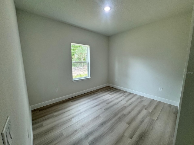 spare room featuring a textured ceiling and light hardwood / wood-style flooring