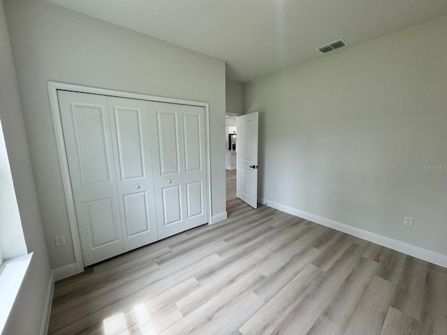 unfurnished bedroom featuring a closet and light wood-type flooring