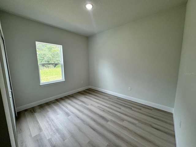 empty room with light hardwood / wood-style floors and a textured ceiling