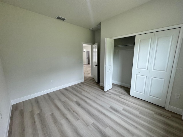 unfurnished bedroom featuring light wood-type flooring and a closet