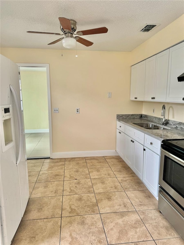 kitchen featuring white refrigerator with ice dispenser, a textured ceiling, white cabinetry, ceiling fan, and stainless steel range with electric cooktop