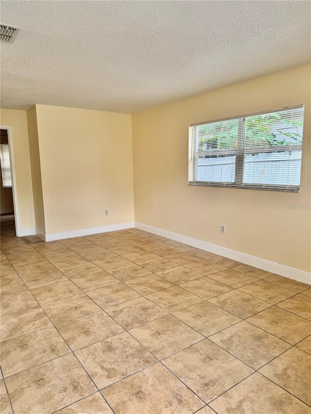 empty room featuring a textured ceiling and light tile patterned floors