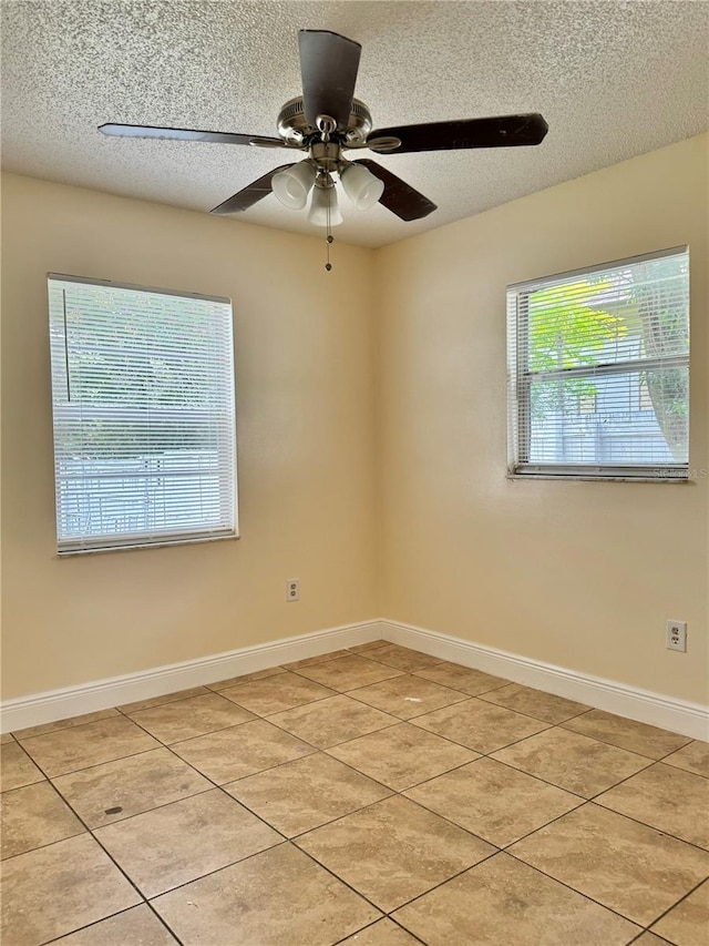 empty room with ceiling fan, light tile patterned floors, and a textured ceiling