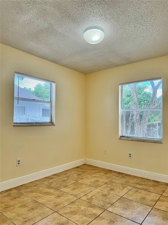 spare room with a textured ceiling and light tile patterned floors