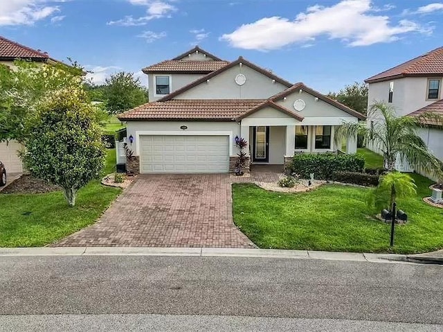 mediterranean / spanish home with an attached garage, stucco siding, a front lawn, a tile roof, and decorative driveway