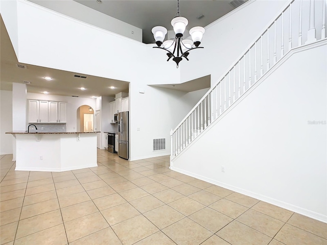 unfurnished living room with a notable chandelier, light tile patterned floors, and sink