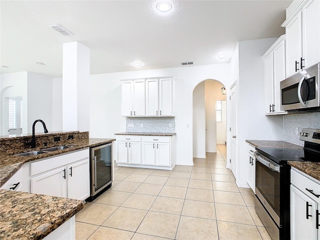 kitchen with beverage cooler, tasteful backsplash, stainless steel appliances, sink, and white cabinetry