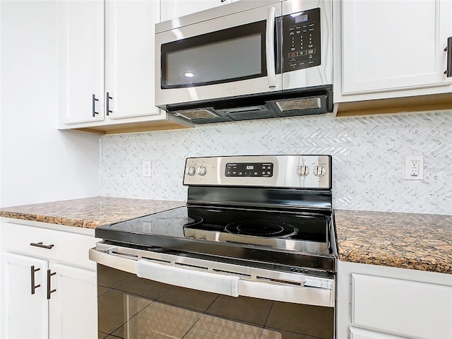 kitchen featuring tasteful backsplash, tile patterned flooring, stainless steel appliances, white cabinetry, and dark stone countertops