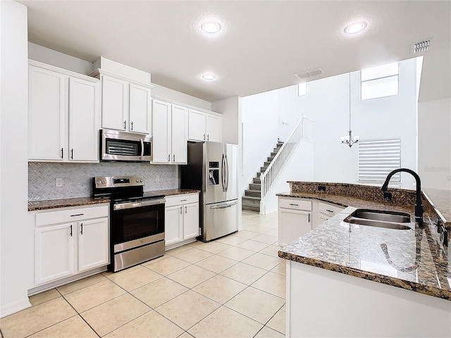 kitchen featuring dark stone counters, white cabinetry, tasteful backsplash, stainless steel appliances, and sink