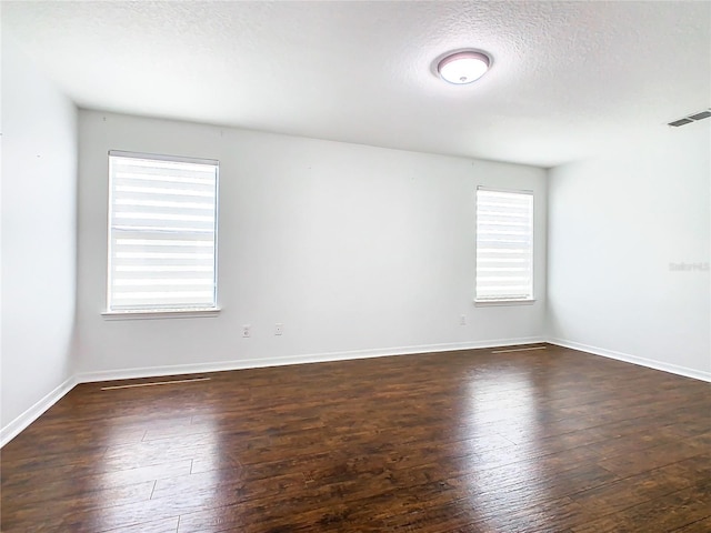 unfurnished room featuring plenty of natural light, dark hardwood / wood-style flooring, and a textured ceiling