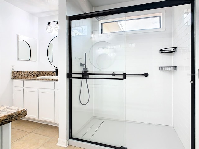 bathroom featuring tile patterned flooring, a shower with shower door, and vanity