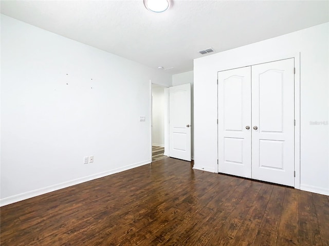 unfurnished bedroom with a closet and dark hardwood / wood-style flooring