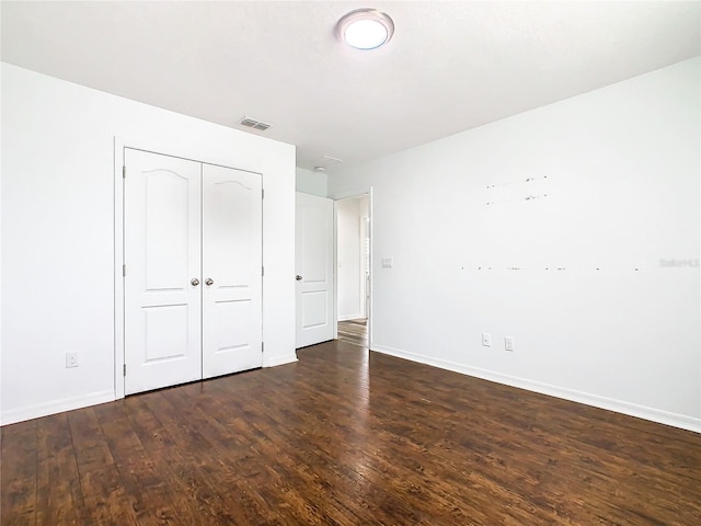 unfurnished bedroom featuring a closet and dark hardwood / wood-style flooring