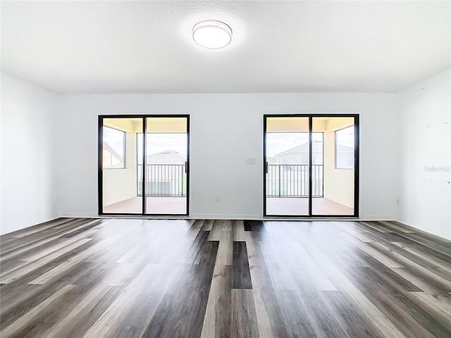 spare room with dark wood-type flooring and a healthy amount of sunlight