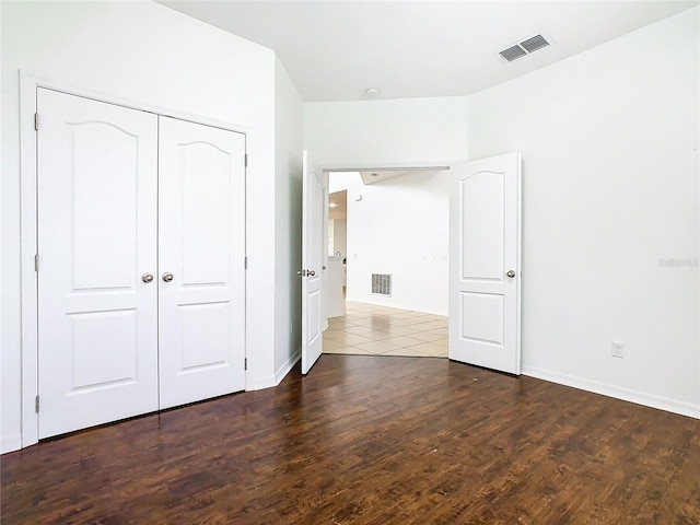 unfurnished bedroom with dark wood-type flooring and a closet