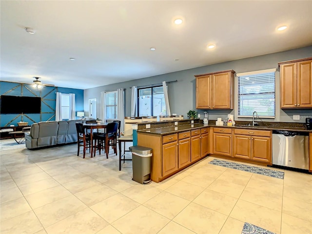 kitchen with dark stone counters, dishwasher, kitchen peninsula, sink, and ceiling fan