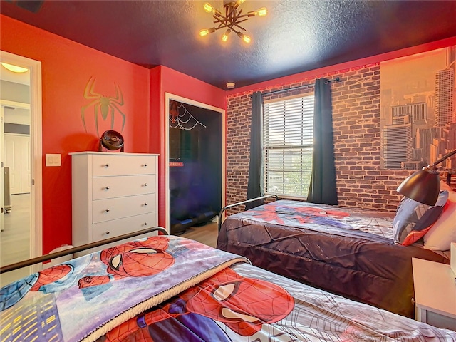 bedroom featuring a closet, a textured ceiling, and brick wall