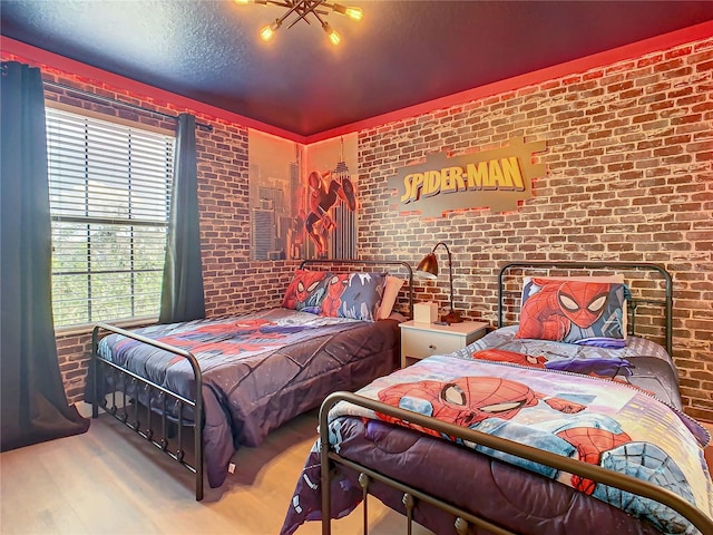 bedroom featuring a textured ceiling, brick wall, and wood-type flooring