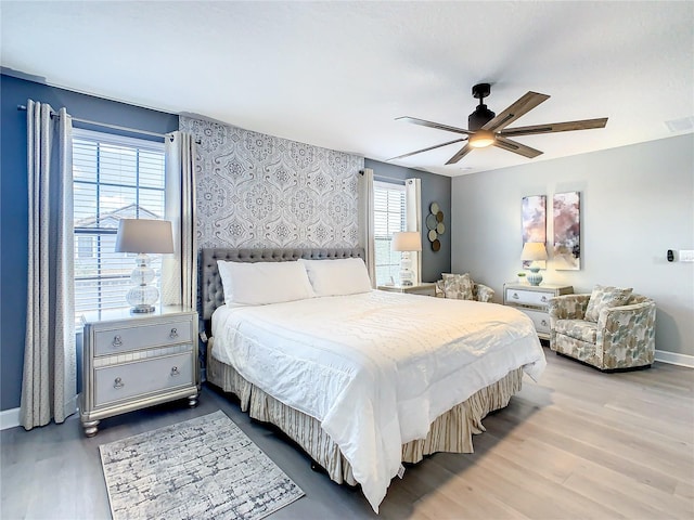 bedroom featuring ceiling fan, wood-type flooring, and multiple windows